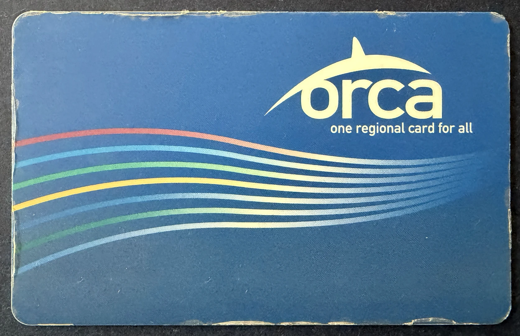 Well-used blue ORCA transit card with multicolored curved lines