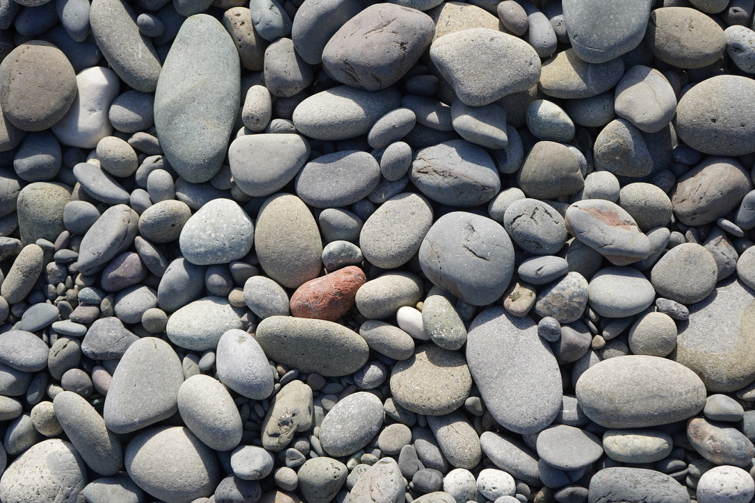 A collection of stones of various shades of gray and a single orange stone near the center